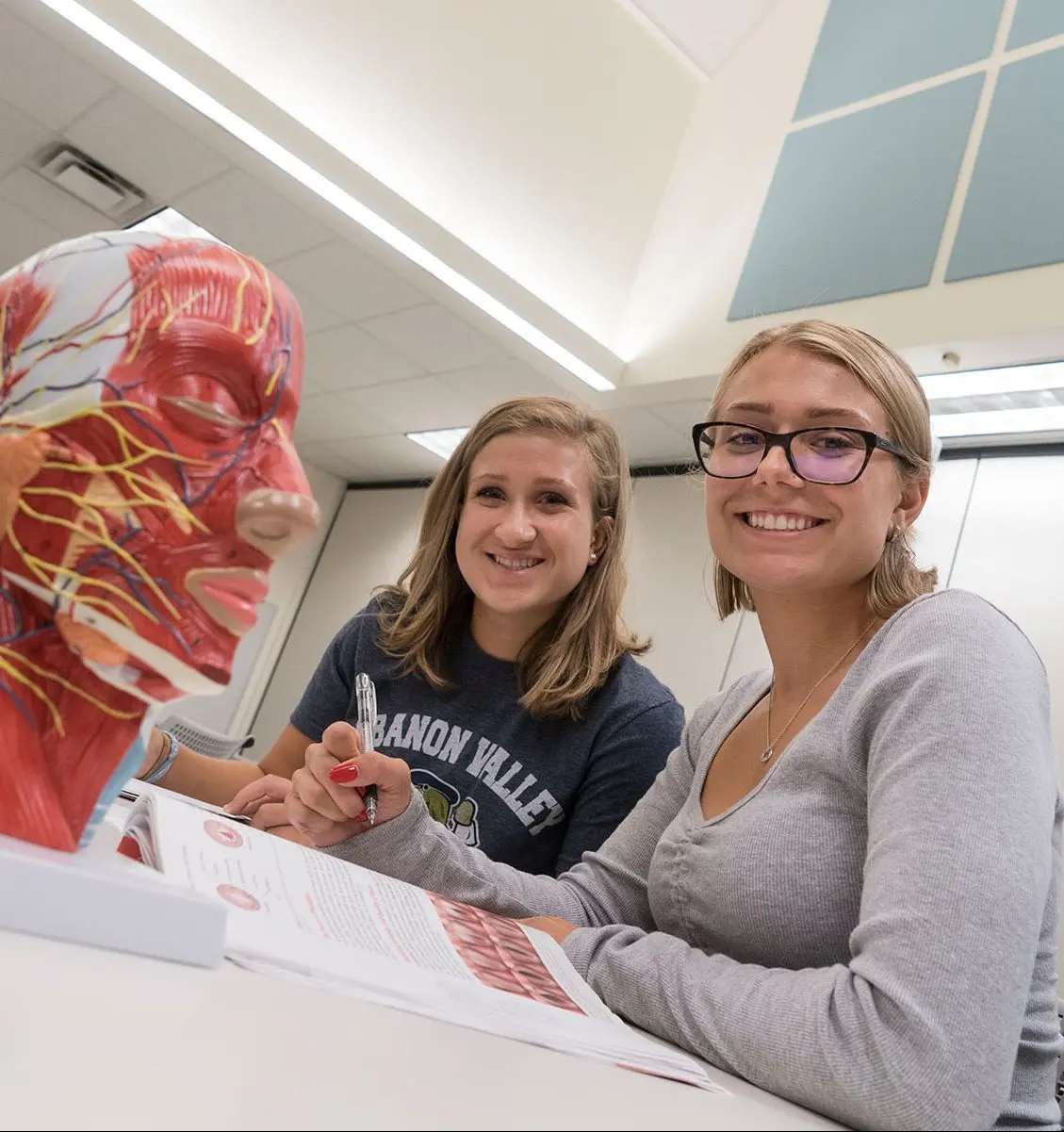 Two students in class next to a scientific model.