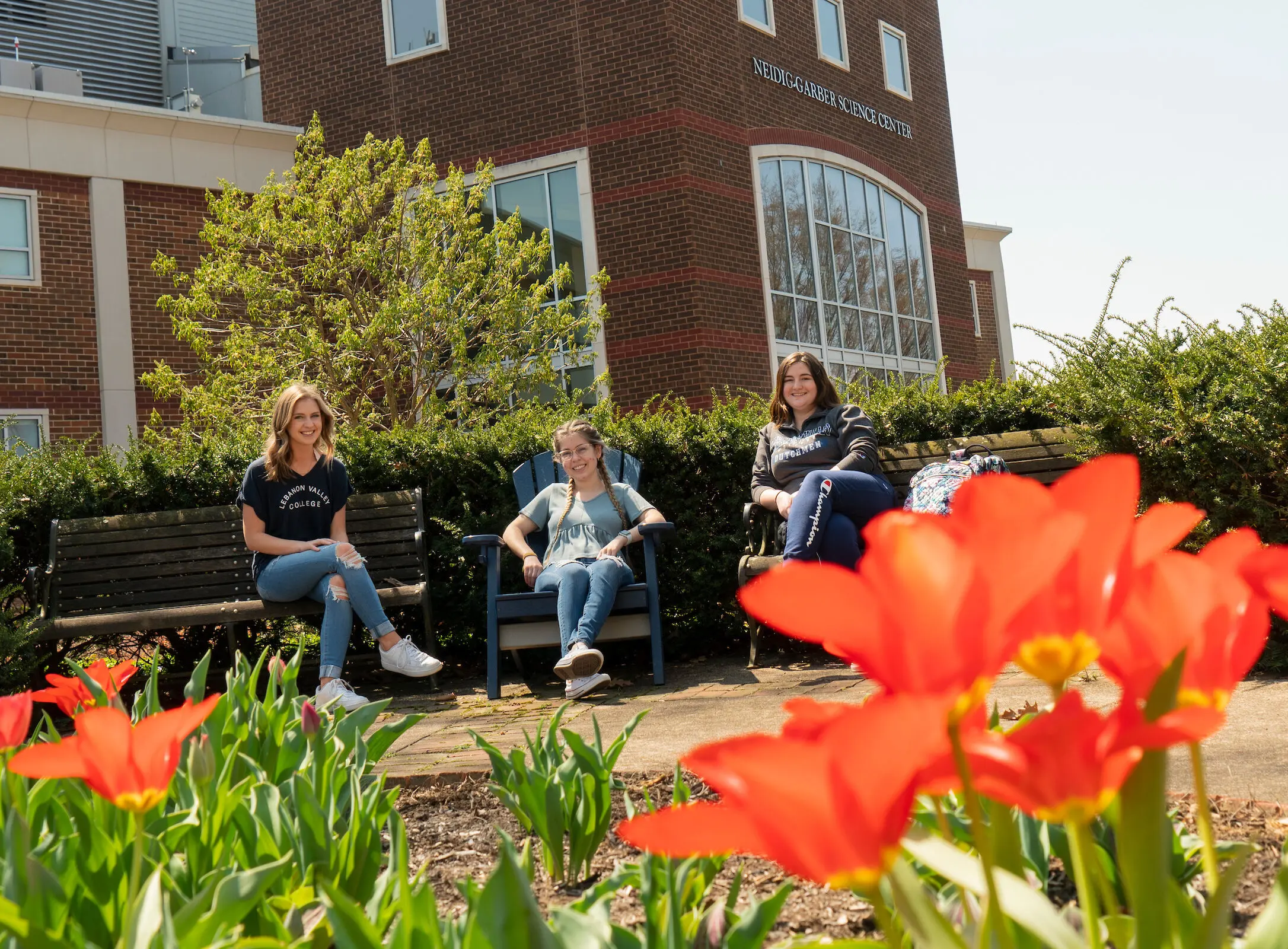 Students sit outside campus building in spring