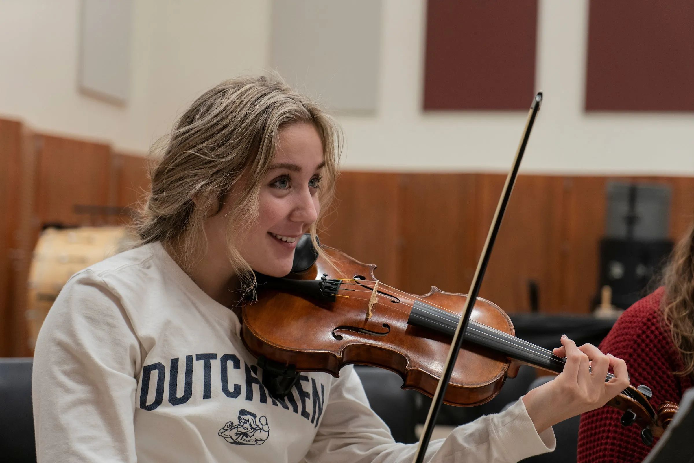 Student holds violin during strings class