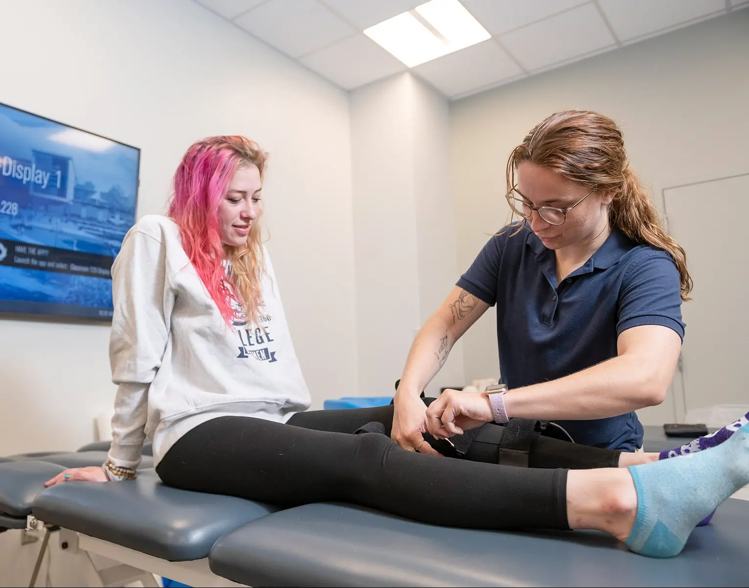 Student wrapping bandage around athlete's leg