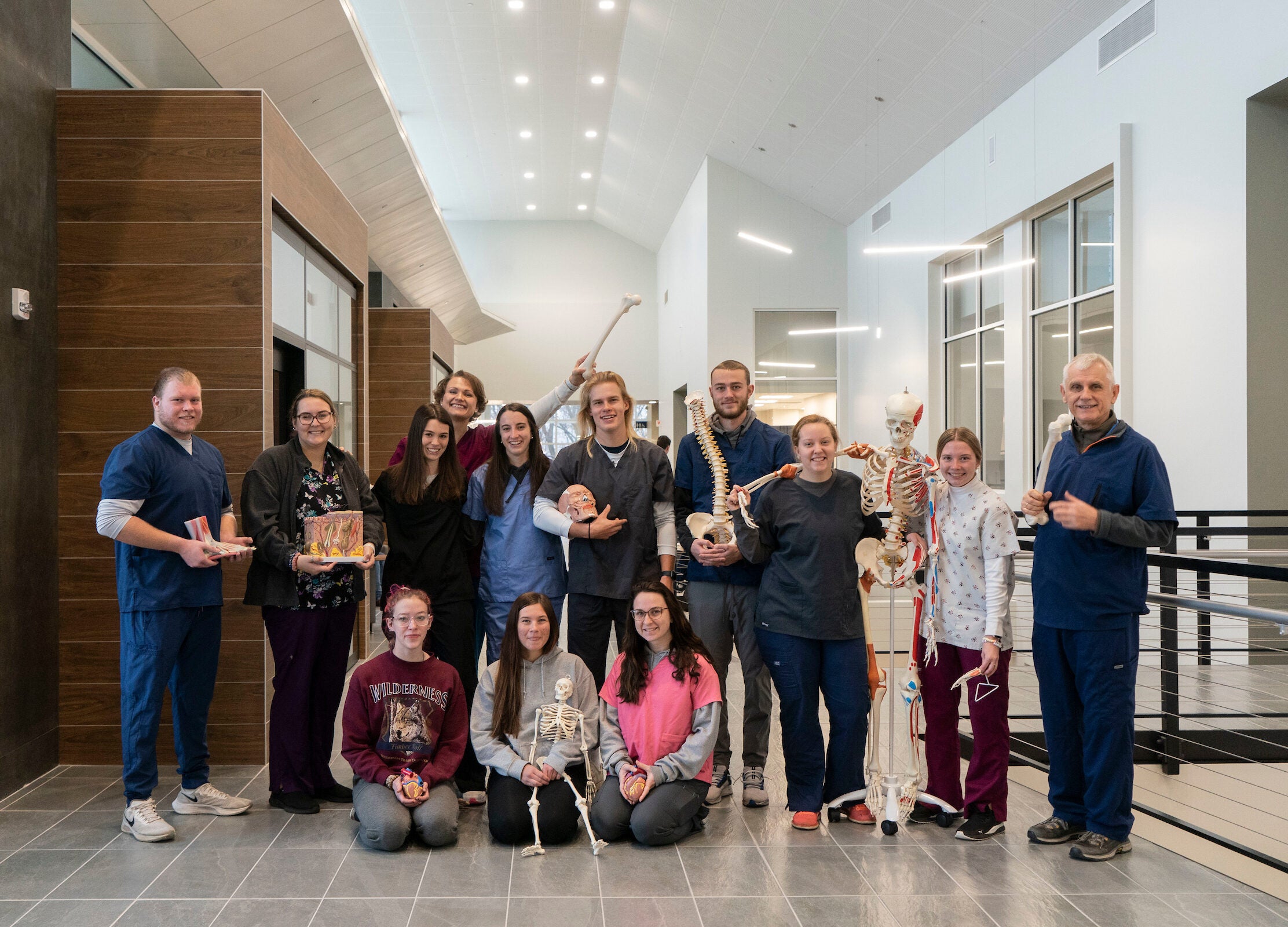 Athletic training students and faculty pose with skeletons and body models