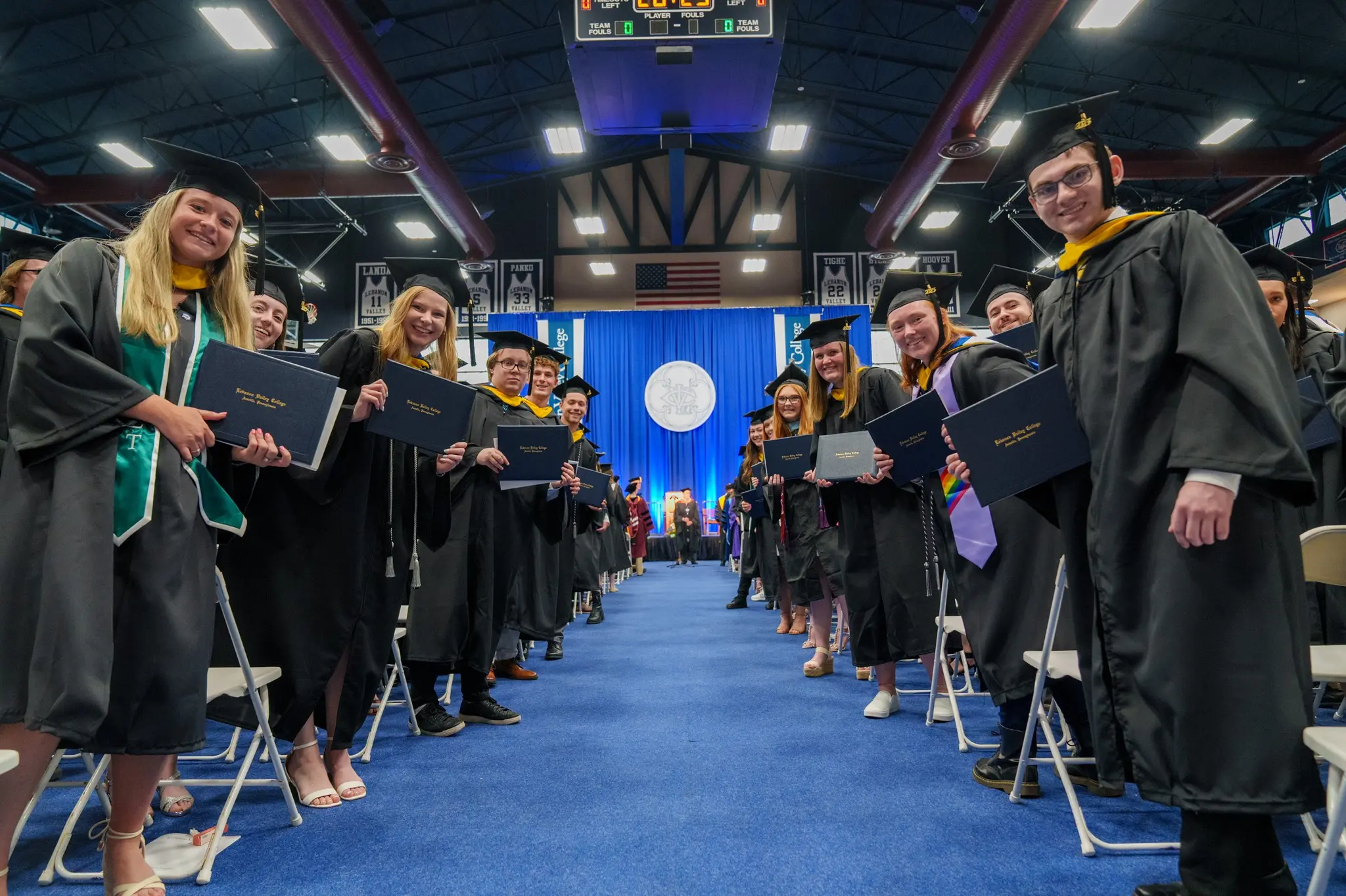 Students pose with diplomas down aisle at Commencement ceremony