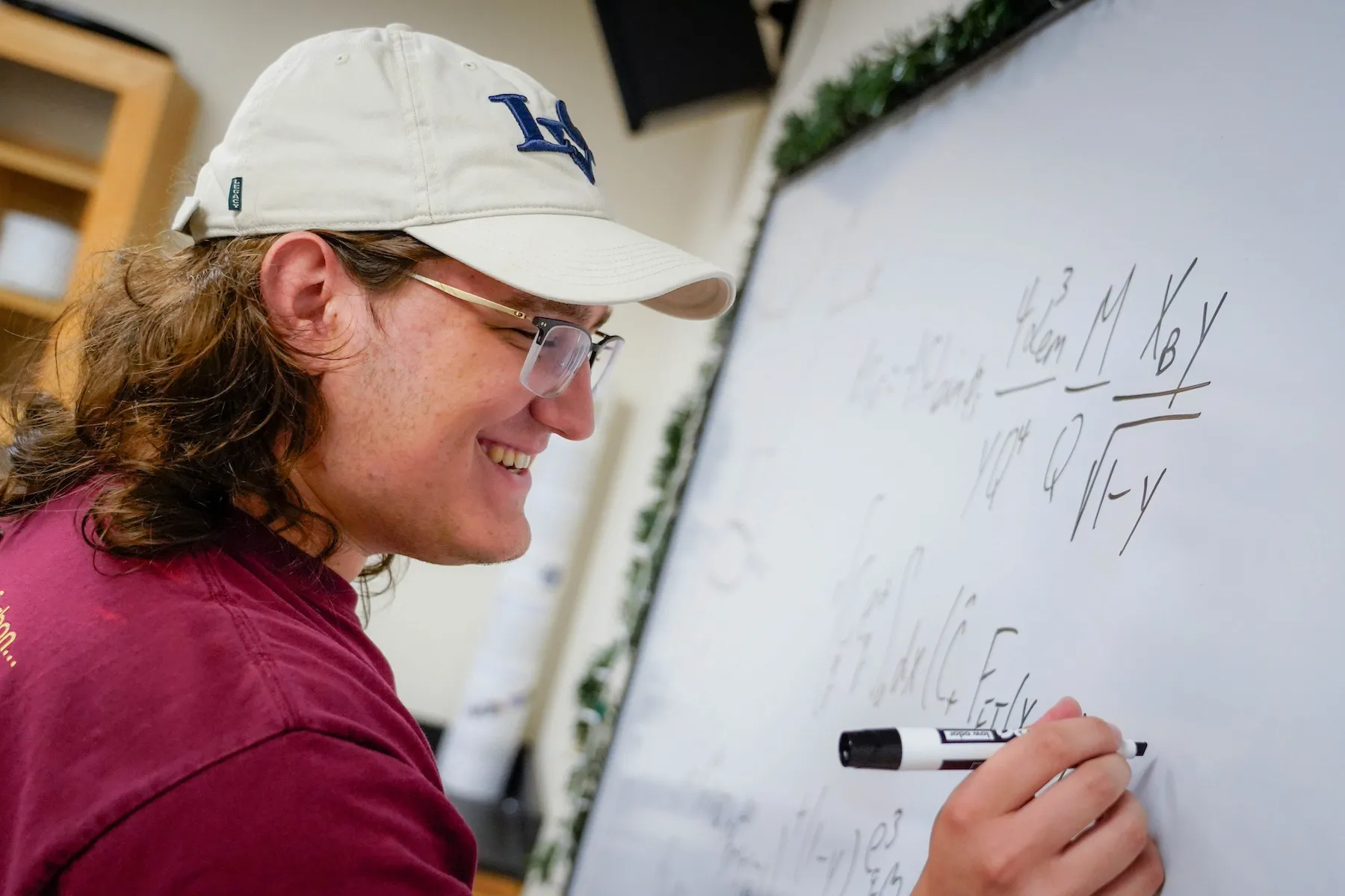Student writes on board during physics summer research over summer