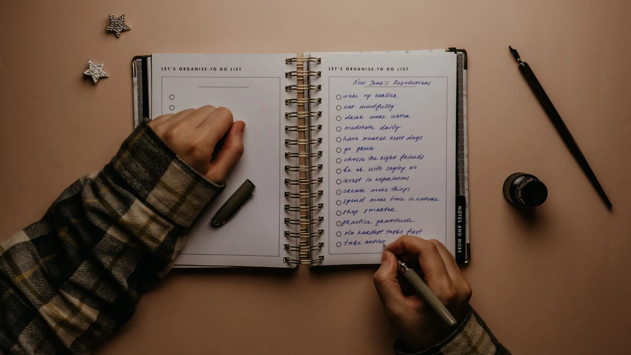 Person writes New Year's resolutions in notebook